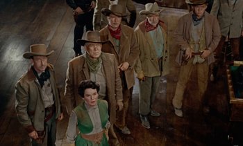 Movie still from “Johnny Guitar” (1954), directed by Nicholas Ray – A group of men and a woman walking down a street; Wide shot, High angle