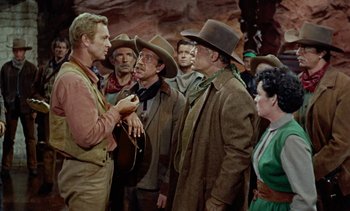 Movie still from “Johnny Guitar” (1954), directed by Nicholas Ray – A group of men and women standing next to each other; Medium shot, Over the shoulder angle