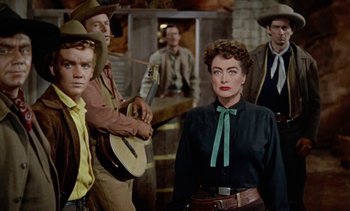 Movie still from “Johnny Guitar” (1954), directed by Nicholas Ray – A group of people standing next to each other in a room; Medium shot, Over the shoulder angle
