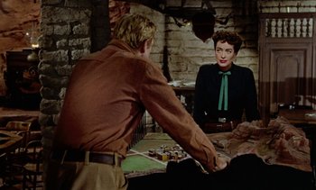 Movie still from “Johnny Guitar” (1954), directed by Nicholas Ray – A man and a woman sitting at a table in front of a brick wall; Medium shot, Over the shoulder angle