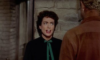 Movie still from “Johnny Guitar” (1954), directed by Nicholas Ray – A person wearing a black shirt and a green bow tie; Close Up shot, Over the shoulder angle
