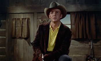 Movie still from “Johnny Guitar” (1954), directed by Nicholas Ray – A man wearing a cowboy hat sitting on a chair; Medium shot, Low angle