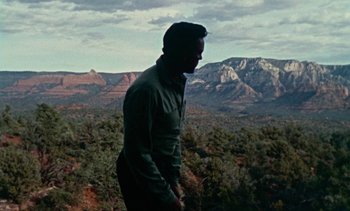Movie still from “Johnny Guitar” (1954), directed by Nicholas Ray – A man standing on top of a hill looking at the mountains; Wide shot, High angle
