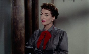 Movie still from “Johnny Guitar” (1954), directed by Nicholas Ray – An older woman wearing a red bow tie and black gloves; Close Up shot, Over the shoulder angle