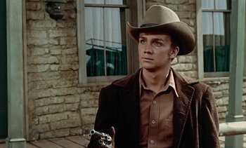 Movie still from “Johnny Guitar” (1954), directed by Nicholas Ray – A man wearing a cowboy hat and holding a gun; Close Up shot, Over the shoulder angle