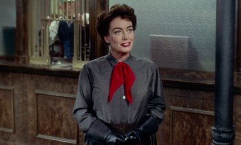 Movie still from “Johnny Guitar” (1954), directed by Nicholas Ray – A woman with a red bow tie standing next to a counter; Medium shot, Over the shoulder angle