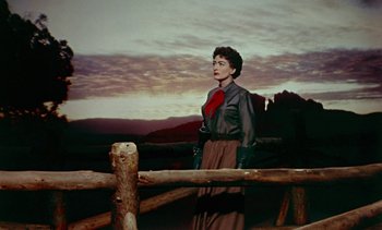 Movie still from “Johnny Guitar” (1954), directed by Nicholas Ray – A woman standing in front of a wooden rail fence; Wide shot, Low angle