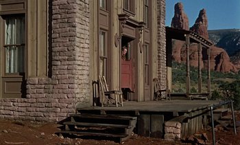 Movie still from “Johnny Guitar” (1954), directed by Nicholas Ray – A person standing in front of an open door of a house; Wide shot, Low angle