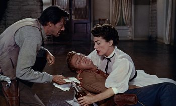 Movie still from “Johnny Guitar” (1954), directed by Nicholas Ray – A man and a woman holding a bottle of beer and another man holding a knife; Medium shot, High angle