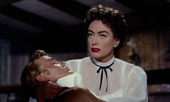 Movie still from “Johnny Guitar” (1954), directed by Nicholas Ray – A woman in a white blouse is holding a man in a black tie; Close Up shot, Over the shoulder angle