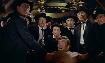 Movie still from “Johnny Guitar” (1954), directed by Nicholas Ray – A group of men and a woman in black suits and black hats; Medium shot, Low angle