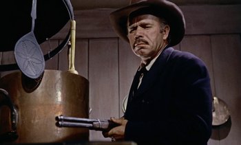 Movie still from “Johnny Guitar” (1954), directed by Nicholas Ray – A man in a cowboy hat holding a gun; Medium shot, Low angle