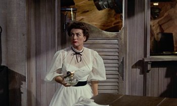 Movie still from “Johnny Guitar” (1954), directed by Nicholas Ray – A woman in a white dress holding a cat; Medium shot, Low angle
