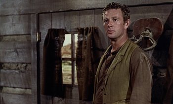 Movie still from “Johnny Guitar” (1954), directed by Nicholas Ray – A man standing in front of a window in a barn; Medium shot, Over the shoulder angle