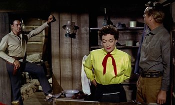 Movie still from “Johnny Guitar” (1954), directed by Nicholas Ray – A woman wearing a yellow shirt and a red bow tie; Medium shot, Over the shoulder angle