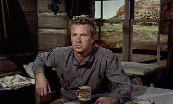 Movie still from “Johnny Guitar” (1954), directed by Nicholas Ray – A man sitting at a table holding a mug; Medium shot, Low angle