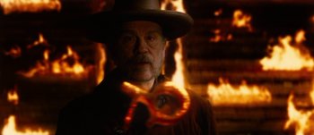 Movie still from “Jonah Hex” (2010), directed by Jimmy Hayward – A man in a cowboy hat is standing in front of a fire; Close Up shot, Over the shoulder angle