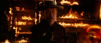 Movie still from “Jonah Hex” (2010), directed by Jimmy Hayward – An old man wearing a hat standing in front of a fire pit; Medium shot, Low angle