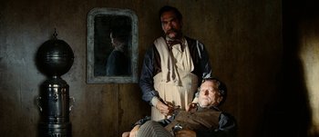 Movie still from “Jonah Hex” (2010), directed by Jimmy Hayward – A man sitting in front of a mirror while another man stands next to him; Medium shot, Over the shoulder angle