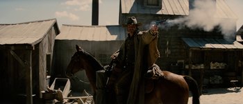 Movie still from “Jonah Hex” (2010), directed by Jimmy Hayward – A man holding a gun while standing on top of a horse; Medium shot, Low angle