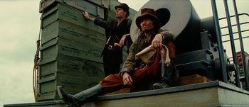 Movie still from “Jonah Hex” (2010), directed by Jimmy Hayward – Two men dressed in period clothing sitting on a wall; Medium shot, Low angle