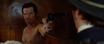 Movie still from “Jonah Hex” (2010), directed by Jimmy Hayward – A shirtless man holding a gun in front of a mirror; Close Up shot, Low angle