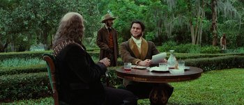 Movie still from “Jonah Hex” (2010), directed by Jimmy Hayward – A man sitting at a table in front of two other men; Medium shot, Over the shoulder angle