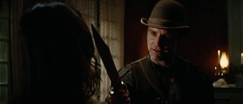 Movie still from “Jonah Hex” (2010), directed by Jimmy Hayward – A man holding a knife in front of a woman; Close Up shot, Over the shoulder angle