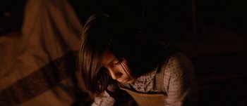 Movie still from “Jonah Hex” (2010), directed by Jimmy Hayward – A young girl sitting in a dark room with her eyes closed; Close Up shot, High angle