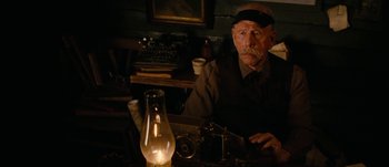 Movie still from “Jonah Hex” (2010), directed by Jimmy Hayward – An older man sitting at a table with a lamp; Medium shot, Low angle