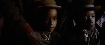 Movie still from “Jonah Hex” (2010), directed by Jimmy Hayward – A young boy wearing a hat in the dark; Close Up shot, Over the shoulder angle