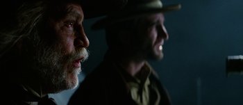 Movie still from “Jonah Hex” (2010), directed by Jimmy Hayward – A man with a beard and a hat is standing next to another man with a beard; Close Up shot, Low angle