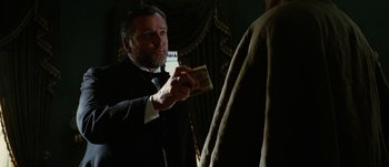 Movie still from “Jonah Hex” (2010), directed by Jimmy Hayward – A man in a suit and tie holding a cell phone; Close Up shot, Low angle