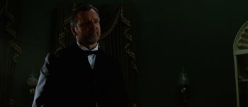 Movie still from “Jonah Hex” (2010), directed by Jimmy Hayward – A man in a suit standing in front of a curtain; Close Up shot, Low angle