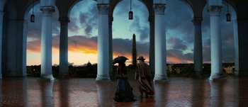 Movie still from “Jonah Hex” (2010), directed by Jimmy Hayward – A man and a woman under an umbrella in front of an obelisk; Wide shot, Low angle