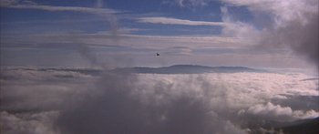 Movie still from “Jonathan Livingston Seagull” (1973), directed by Hall Bartlett – An airplane is flying above the clouds on a sunny day; Extreme Wide shot, Low angle