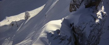 Movie still from “Jonathan Livingston Seagull” (1973), directed by Hall Bartlett – A person is skiing down a steep mountain slope; Extreme Wide shot, Low angle