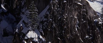 Movie still from “Jonathan Livingston Seagull” (1973), directed by Hall Bartlett – A pine tree in front of a mountain covered in snow; Extreme Wide shot, High angle