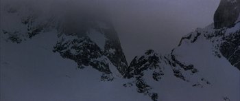 Movie still from “Jonathan Livingston Seagull” (1973), directed by Hall Bartlett – A view of a snowy mountain with a dark sky above it; Extreme Wide shot, Low angle