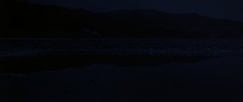 Movie still from “Jonathan Livingston Seagull” (1973), directed by Hall Bartlett – A body of water at night with a mountain in the background; Extreme Wide shot, Low angle