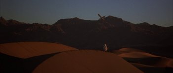 Movie still from “Jonathan Livingston Seagull” (1973), directed by Hall Bartlett – A bird is flying over a sandy beach; Extreme Wide shot, Low angle
