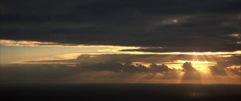 Movie still from “Jonathan Livingston Seagull” (1973), directed by Hall Bartlett – The sun is setting over the ocean with dark clouds in the background; Extreme Wide shot, High angle