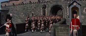 Movie still from “Journey to the Center of the Earth” (1959), directed by Henry Levin – A group of men in kilts marching down a street; Extreme Wide shot, Low angle