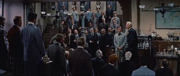 Movie still from “Journey to the Center of the Earth” (1959), directed by Henry Levin – A group of men in suits standing in front of a crowd; Wide shot, Low angle