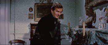 Movie still from “Journey to the Center of the Earth” (1959), directed by Henry Levin – A man in a suit and tie standing in a room; Medium shot, Low angle