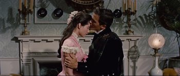 Movie still from “Journey to the Center of the Earth” (1959), directed by Henry Levin – A man and a woman are kissing each other in front of a fireplace; Medium shot, Low angle