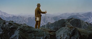 Movie still from “Journey to the Center of the Earth” (1959), directed by Henry Levin – A man standing on top of a mountain holding a pole; Wide shot, Low angle