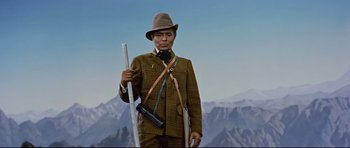 Movie still from “Journey to the Center of the Earth” (1959), directed by Henry Levin – A man in a brown suit and hat holding a rifle; Medium shot, Low angle