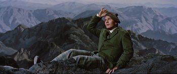 Movie still from “Journey to the Center of the Earth” (1959), directed by Henry Levin – A man sitting on top of a mountain wearing a hat; Medium shot, High angle