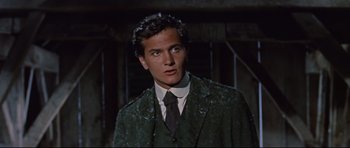 Movie still from “Journey to the Center of the Earth” (1959), directed by Henry Levin – A man wearing a suit and tie standing in front of a building; Close Up shot, Low angle